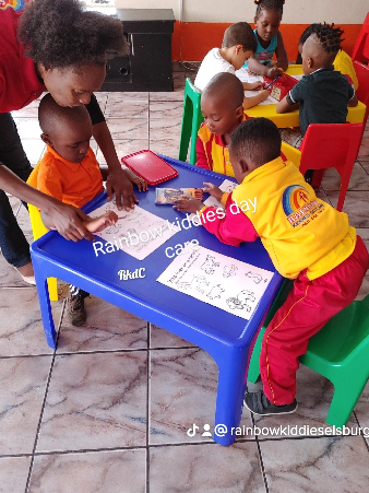 Children working on activities with a teacher at Rainbow Kiddies