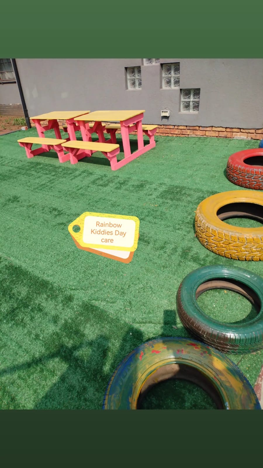 Colourful outdoor tables and play tyres at Rainbow Kiddies