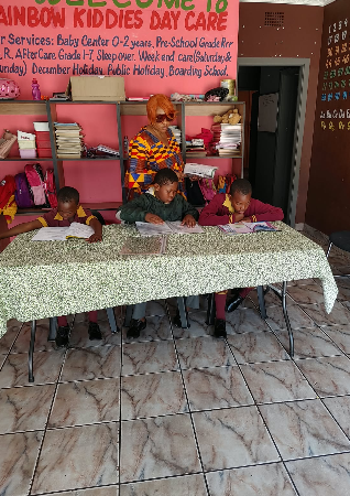 Children reading together with their teacher at Rainbow Kiddies